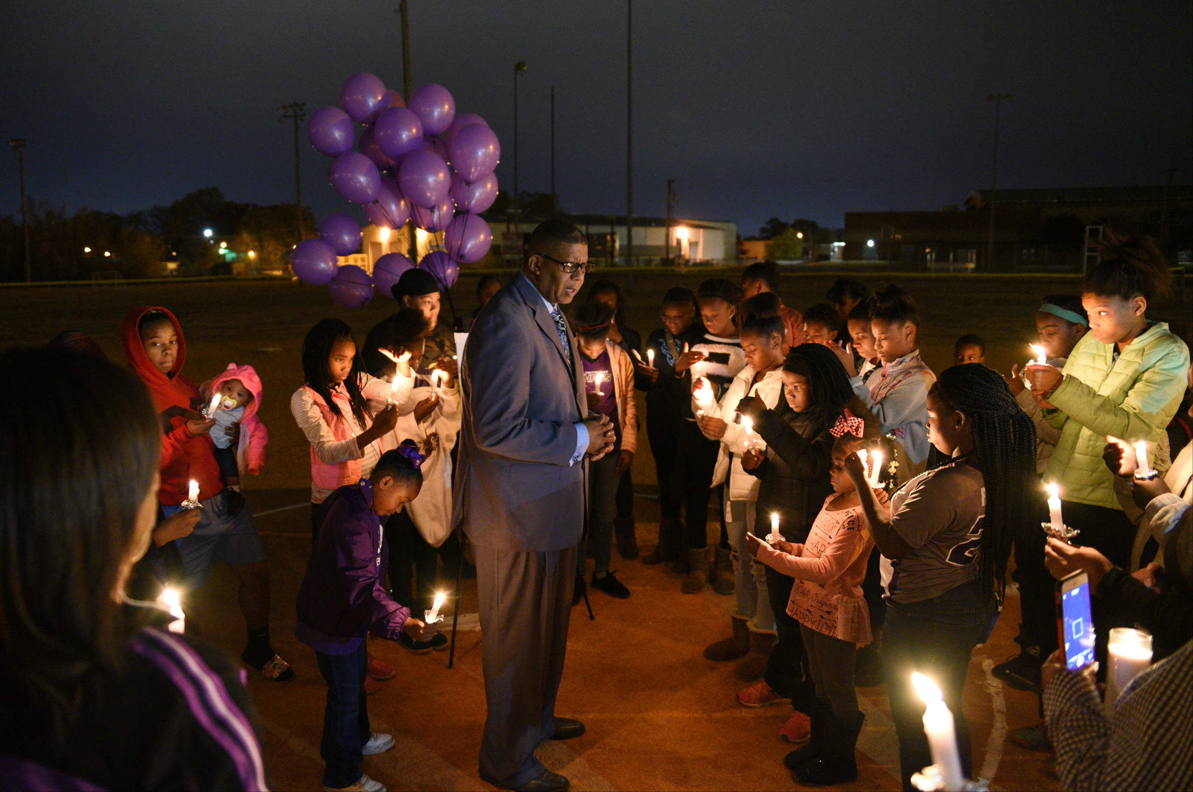 Pastor Todd Lansden leads the group in prayer as they hold candles Wednesday, Nov. 23, 2016, at East Lake Recreation Center during a memorial for Zoie Nash, who was killed in a bus crash this week.