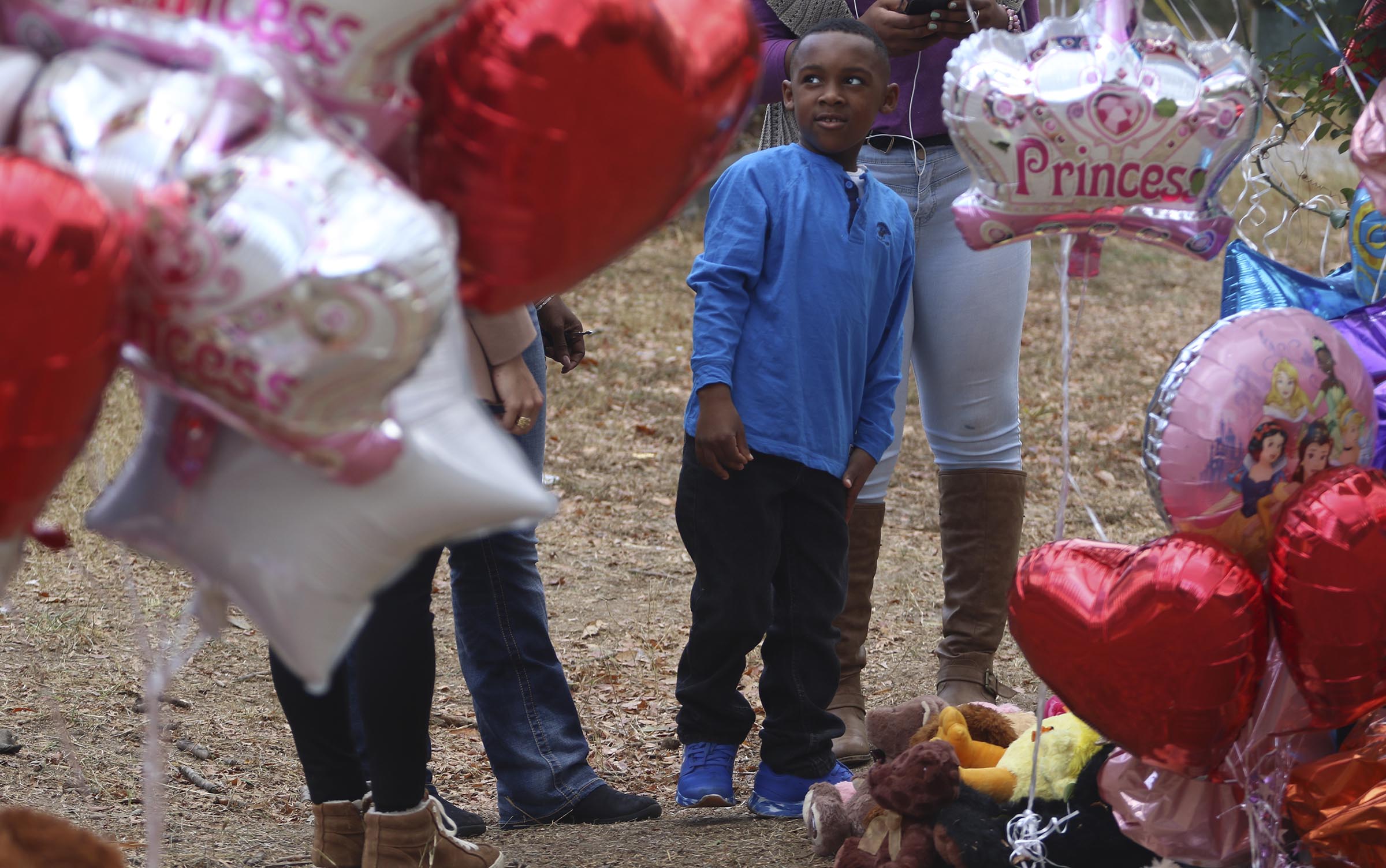 Staff Photo by Dan Henry / The Chattanooga Times Free Press- 11/24/16. Tre Jackson, 5, visits the site of a fatal school bus crash off of Talley Road with his family on Thursday, Nov. 24, 2016, in Chattanooga, Tenn. The makeshift memorial to victims of the Monday crash, which killed 6 Woodmore Elementary students and injured dozens more, has grown since the road was reopened Tuesday.