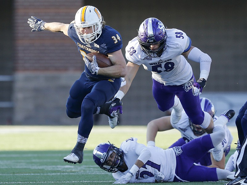 UTC running back Derrick Craine hurdles Weber State cornerback Dre Snowden (27) ahead of linebacker LeGrand Toia (58) during the Mocs' first-round FCS football playoff game against Weber State at Finely Stadium on Saturday, Nov. 26, 2016, in Chattanooga, Tenn. UTC won 45-14.