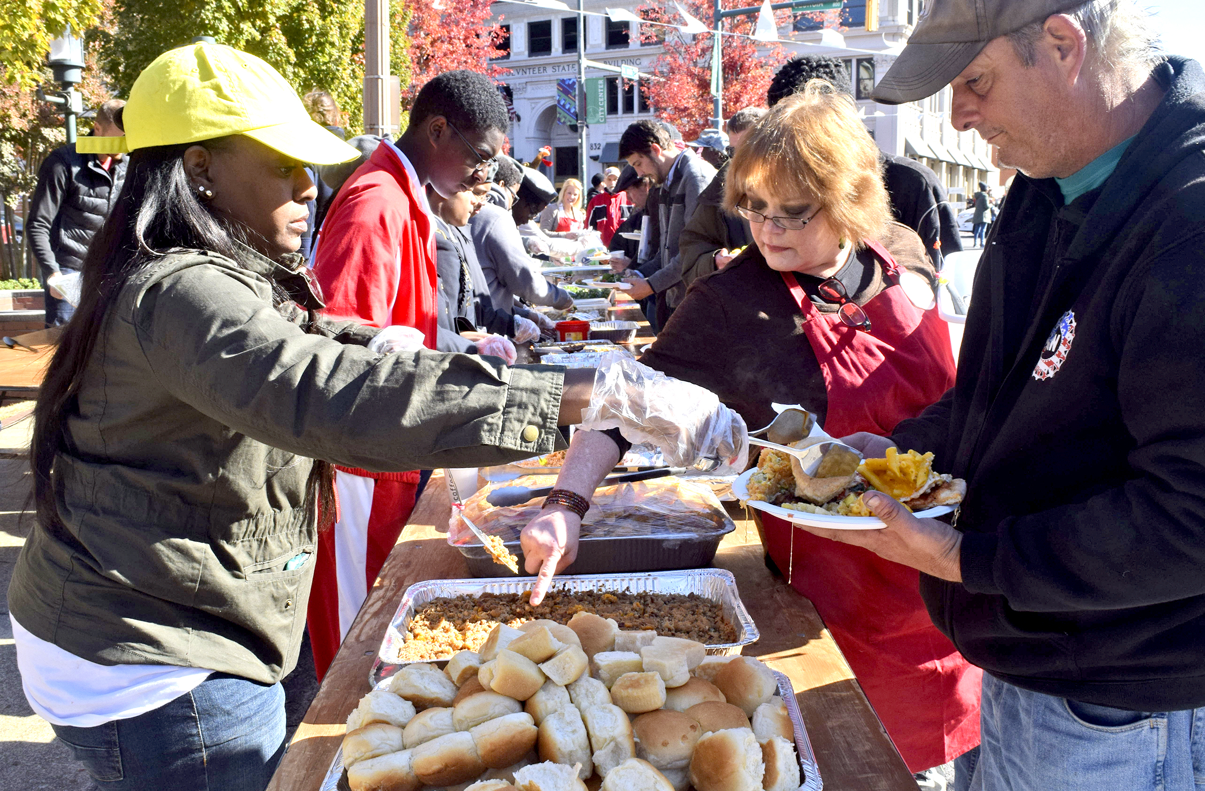 Coretha Kendricks, left, serves a roll to a diner, while Sheila Ruiz, center, checks on the sweet potatoes.