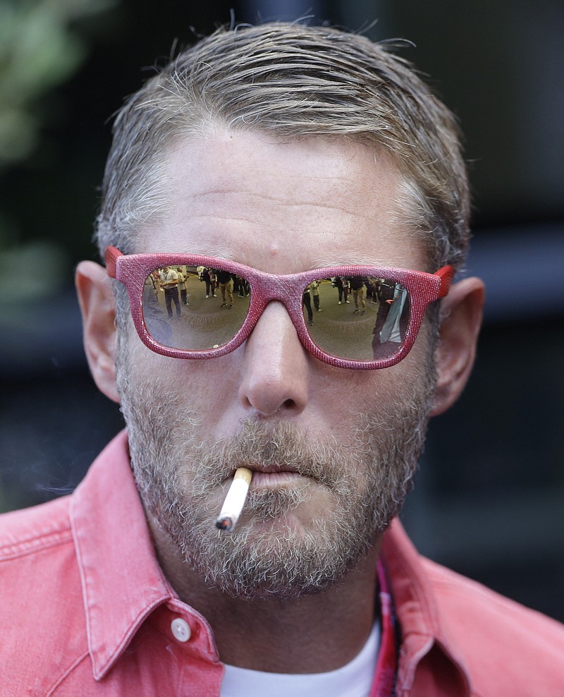 
              FILE- In this Sept. 5, 2015 file photo, Italian entrepreneur Lapo Elkann smokes prior to the start of the third practice session for Sunday's Formula One Italian Grand Prix, at the Monza racetrack, Italy. Police in New York City say the grandson of the Italian founder of Fiat Automobiles was arrested on Saturday, Nov. 26, 2016, after falsely claiming an escort held him against his will. (AP Photo/Luca Bruno, File)
            