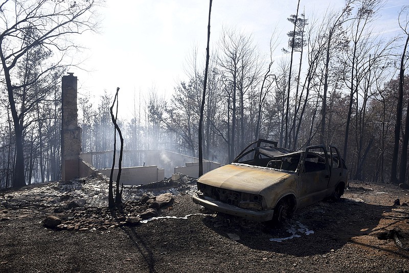 Burned out cars and chimneys are damaged from the wildfires around Gatlinburg, Tenn., on  Tuesday, Nov. 29, 2016.  Rain had begun to fall in some areas, but experts predicted it would not be enough to end the relentless drought that has spread across several Southern states and provided fuel for fires now burning for weeks in states including Tennessee, Georgia and North Carolina. (Michael Patrick/Knoxville News Sentinel via AP)