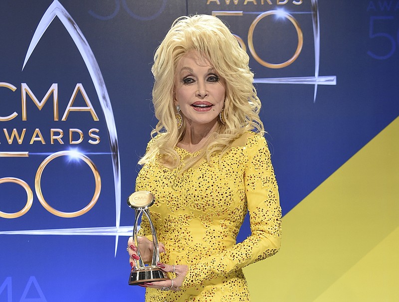 In this Nov. 2, 2016 file photo, Dolly Parton poses in the press room with the Willie Nelson Lifetime Achievement Award during the 50th annual CMA Awards in Nashville. Parton says she's heartbroken about wildfires that tore through the Tennessee county where she grew up, but spared the Dollywood theme park that bears her name. At least 14,000 people have been forced to evacuate the tourist area of Gatlinburg, Tenn., and a dozen people have been injured in the wildfires. (Photo by Evan Agostini/Invision/AP, File)