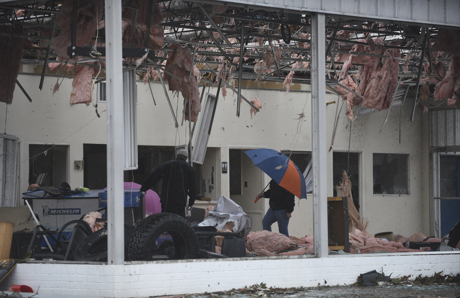 People walk through C & D Tires and Services in Athens, Tenn., Wednesday, Nov. 30, 2016 after a tornado swept through the area early Wednesday morning.