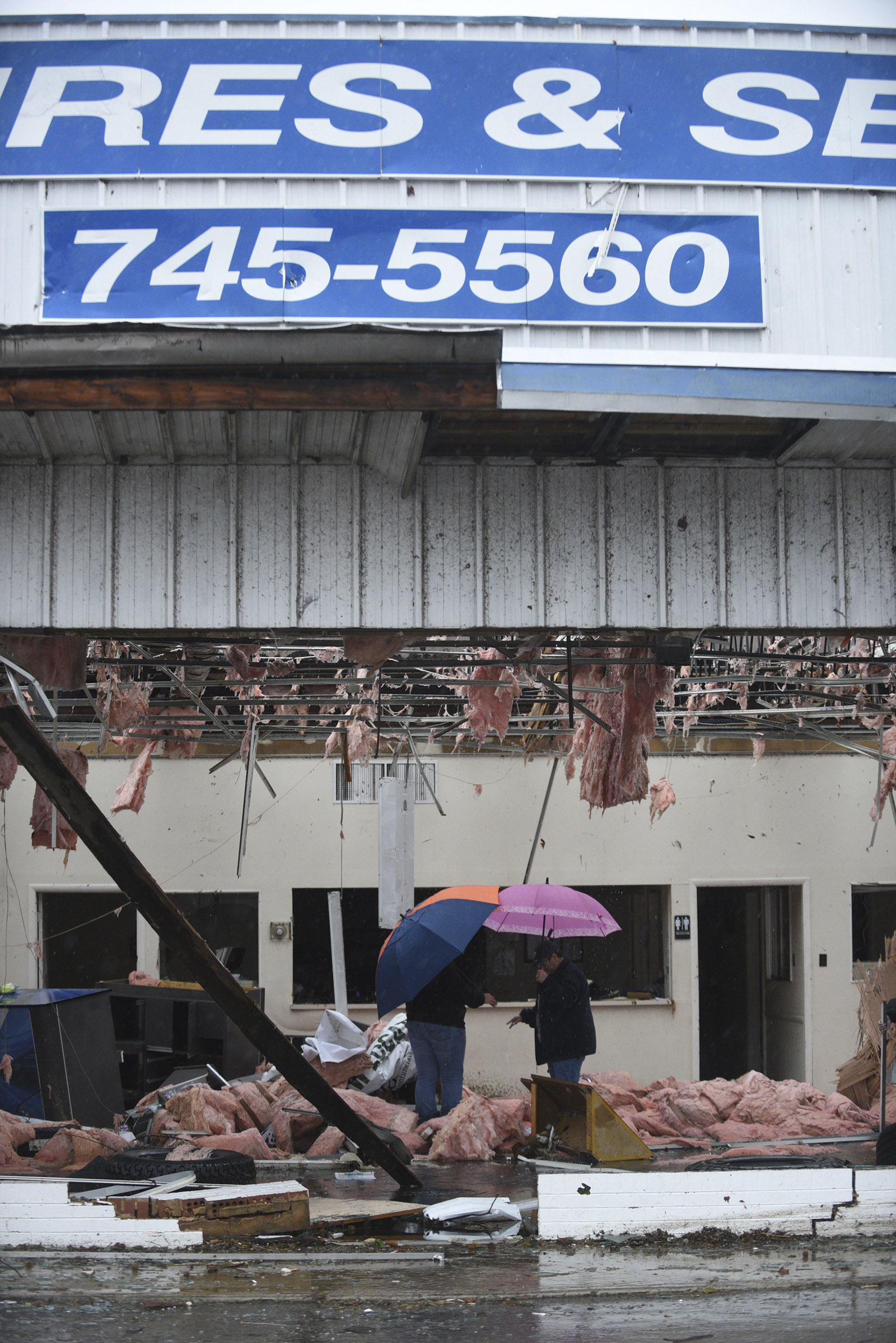 People walk through C & D Tires and Services in Athens Wednesday, Nov. 30, 2016 after a tornado swept through the area early Wednesday morning.