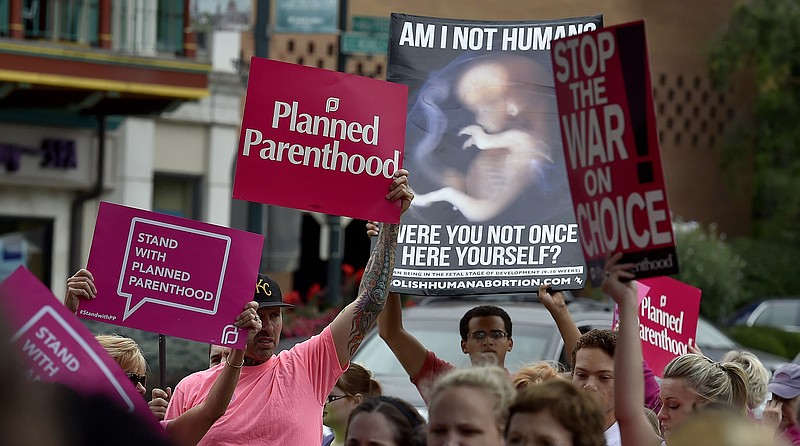 
              FILE - In this Sept. 29, 2015 file photo, people participate in a rally to show support for Planned Parenthood, organized by MoveOn and called "Pink Out Kansas City," as an anti-abortion demonstrator stands amongst them, at the Country Club Plaza,  in Kansas City, Mo. Planned Parenthood and its allies filed lawsuits Wednesday, Nov. 30, 2016, in North Carolina, Missouri and Alaska challenging laws that they view as unconstitutional restrictions on abortion. The restrictions being challenged in Missouri are similar to those that the Supreme Court recently struck down in Texas - they require abortion clinics to meet standards for surgical centers and mandate that their doctors have admitting privileges in nearby hospitals. (John Sleezer  /The Kansas City Star via AP, File)
            