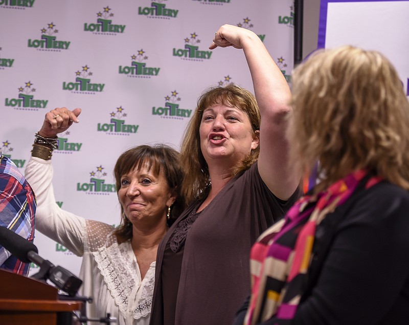 Smokeshop owner Joyce Gregory, left and Amy O'Neal point at each other during a news conference at the Tennessee Lottery Headquarters in Nashville. Tennessee Lottery officials say 20 co-workers at a metal manufacturing plant will split a Powerball jackpot of nearly $421 million. (Lacy Atkins/The Tennessean via AP)
