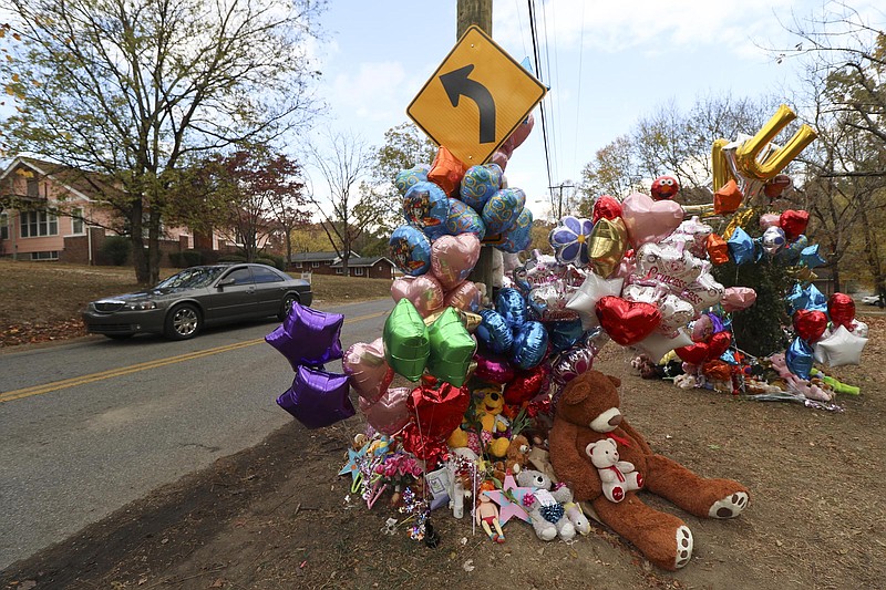 Motorists pass a collection of teddy bears, mementos and balloons placed at the site of a Nov. 21 fatal school bus crash on Talley Road.