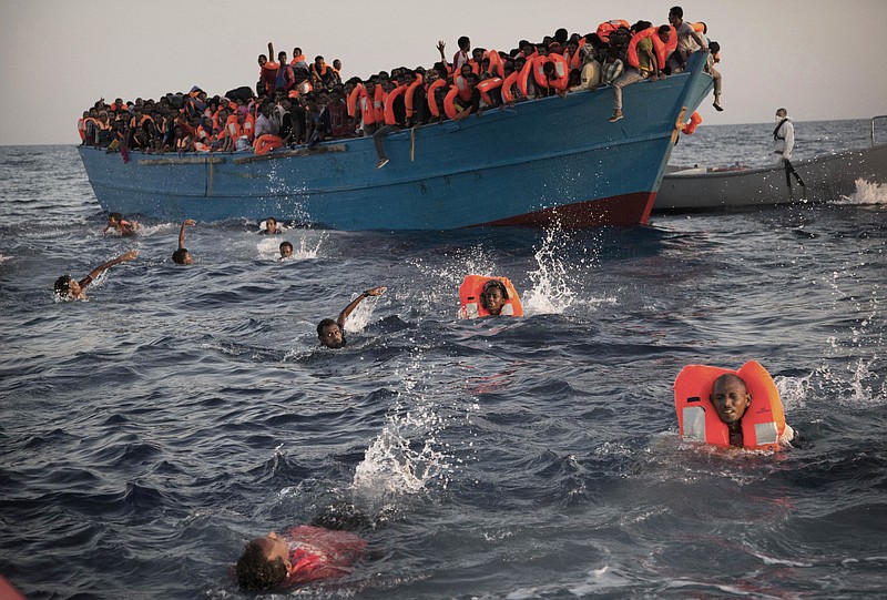 
              FILE - In this Aug. 29, 2016 file photo, migrants, most from Eritrea, jump into the water from a crowded wooden boat as they are helped by members of a nongovernmental organization during a rescue operation in the Mediterranean Sea, about 13 miles (20 kilometers) north of Sabratha, Libya. A new EU report accessed by The Associated Press on Thursday, Dec. 1, 2016, says that Libya’s coastal cities are generating up to 325 million euros ($346 million) in revenue each year from people smuggling. (AP Photo/Emilio Morenatti, File)
            