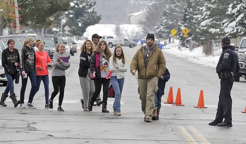 
              A police officer escorts students down the street following a school lockdown at Mueller Park Junior High after a student fired a gun into the ceiling Thursday, Dec. 1, 2016, in Bountiful, Utah. Police said two fast-acting Utah parents disarmed their son in the hallway of the Utah junior high school Thursday after the teenager brought the family's shotgun and handgun to school, discharging at least one round without injuring anyone. (AP Photo/Rick Bowmer)
            