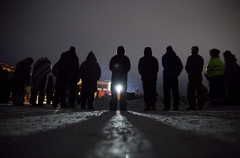 
              In this Wednesday, Nov. 30, 2016 photo, people form a circle for the morning prayer at the Oceti Sakowin camp where many have gathered to protest the Dakota Access pipeline near Cannon Ball, N.D. President-elect Donald Trump supports completion of the disputed Dakota Access oil pipeline in the Midwest, a view based on policy and not the billionaire businessman’s investments in a partnership building the $3.8 billion pipeline. (AP Photo/David Goldman)
            