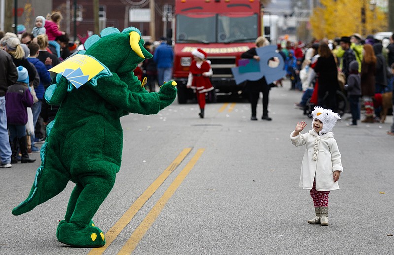 Lola Therrien waves to a person dressed as a dinosaur in the parade during the Mainx24 Festival on Main Street on Saturday, Dec. 3, 2016, in Chattanooga, Tenn. The annual 24-hour neighborhood festival celebrates Main Street and included a pancake breakfast at the fire station, music, arts, and caroling.
