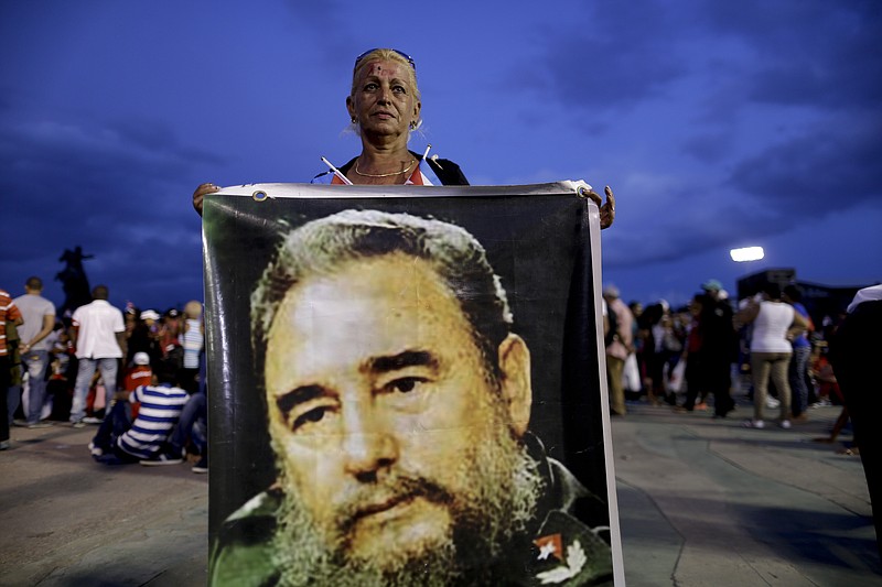 
              A woman holds a picture of Fidel Castro before a rally honoring Cuba's late leader at Antonio Maceo plaza in Santiago, Cuba, Saturday, Dec. 3, 2016. After a four-day journey across the country through small towns and cities where his rebel army fought its way to power nearly 60 years ago, Castro's remains arrived Saturday to Santiago where they will be buried the following day. (AP Photo/Natacha Pisarenko)
            