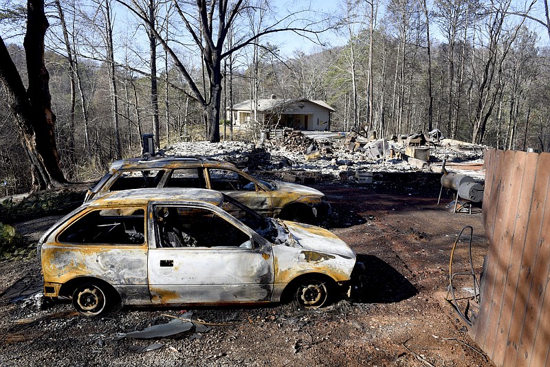 
              Charred home and cars sit on a property, while a neighbor's home, background, is undamaged Thursday, Dec. 1, 2016, in Gatlinburg, Tenn. A devastating wildfire destroyed numerous homes and buildings on Monday.   (Michael Patrick/Knoxville News Sentinel via AP)
            