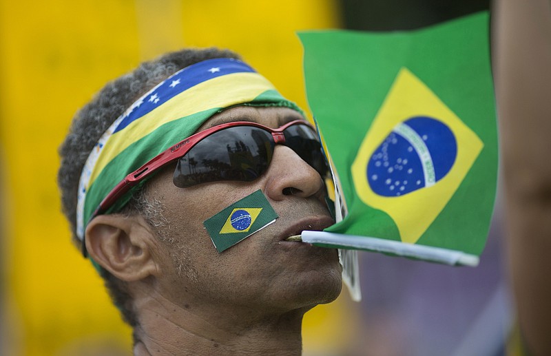 
              A man holds a Brazil's national flag with his mouth during a protest against corruption on Copacabana beach, in Rio de Janeiro, Brazil, Sunday, Dec. 4, 2016. Thousands of protesters are crowding Rio de Janeiro's beachfront to express disgust with public corruption and to support the judges and prosecutors pursuing those crimes. Protests are also under way Sunday in other Brazilian cities. (AP Photo/Silvia Izquierdo)
            