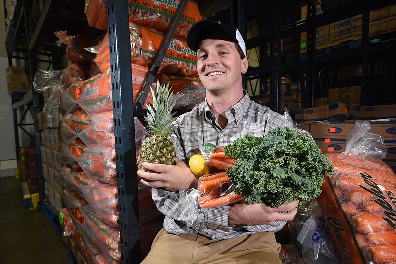 In the warehouse at Dixie Produce, Asa Swift, operator of three new Juice Bar franchises in Chattanooga, holds examples of fresh produce that will be included in his healthy drink treats. 