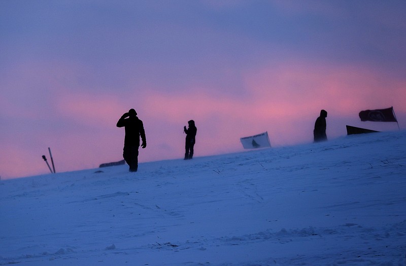 
              People walk along a snowy hillside at the Oceti Sakowin camp where people have gathered to protest the Dakota Access oil pipeline in Cannon Ball, N.D., Monday, Dec. 5, 2016. Many Dakota Access oil pipeline opponents who've gathered for months in the camp in southern North Dakota are committed to staying despite wintry weather and demands that they leave. (AP Photo/David Goldman)
            