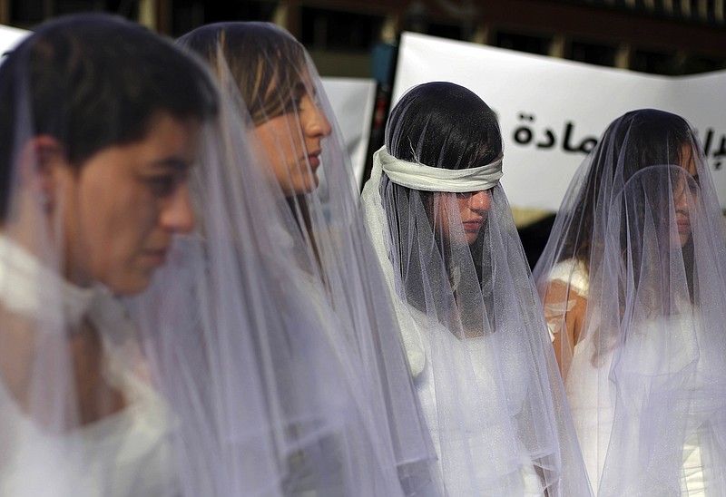 
              A dozen Lebanese women, dressed as brides in white wedding dresses stained with fake blood and bandaging their eyes, knees and hands stand in front of the government building in downtown Beirut, Lebanon, Tuesday, Dec. 6, 2016. The activists are protesting a Lebanese law that allows a rapist to get away with his crime if he marries the survivor. The law, in place since the late 1940s, is currently reviewed in Lebanese parliament. Campaigners against the law are calling on lawmakers to repeal the law during their meeting Wednesday. (AP Photo/Bilal Hussein)
            