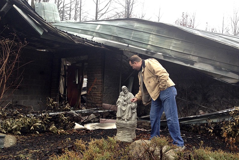 
              In this Monday, Dec. 6, 2016 photo, Senior Pastor Kim McCroskey inspects a statue outside the remains of the family life center at Roaring Fork Baptist Church in Gatlinburg, Tenn. The church and the center burned down in wildfires a week earlier. (AP Photo/Jonathan Mattise)
            