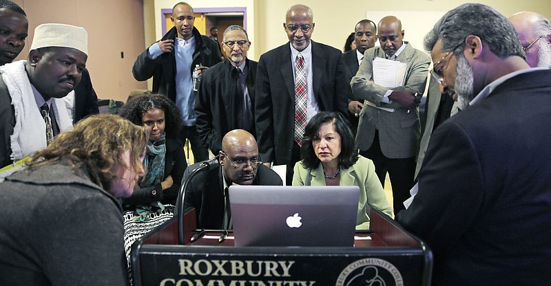 
              FILE - In this March 31, 2015 file photo, Muslim, Christian, minority and government leaders fix their eyes on a laptop screen showing a video as part of a federal pilot program called Countering Violent Extremism, at Roxbury Community College in Boston. The federally financed effort meant to stem the rise of homegrown extremists is finally underway in Massachusetts after years of delays and strong local opposition, and just weeks before a new administration takes over in the White House. The state picked three local organizations to use $210,000 in federal Countering Violent Extremism funding earlier this month. Seated at center right is Carmen Ortiz, U.S. Attorney for Massachusetts. (AP Photo/Charles Krupa, File)
            