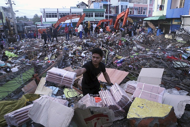 
              A man salvages printed materials from under the rubble of a shop flattened in Wednesday's earthquake at a market in Meureudu, Aceh province, Indonesia, Thursday, Dec. 8, 2016. Rescue workers, soldiers and police combed through the rubble of a devastated town in Indonesia's Aceh province early Thursday, resuming a search for earthquake survivors that was halted at night by rain and blackouts. (AP Photo/Heri Juanda)
            