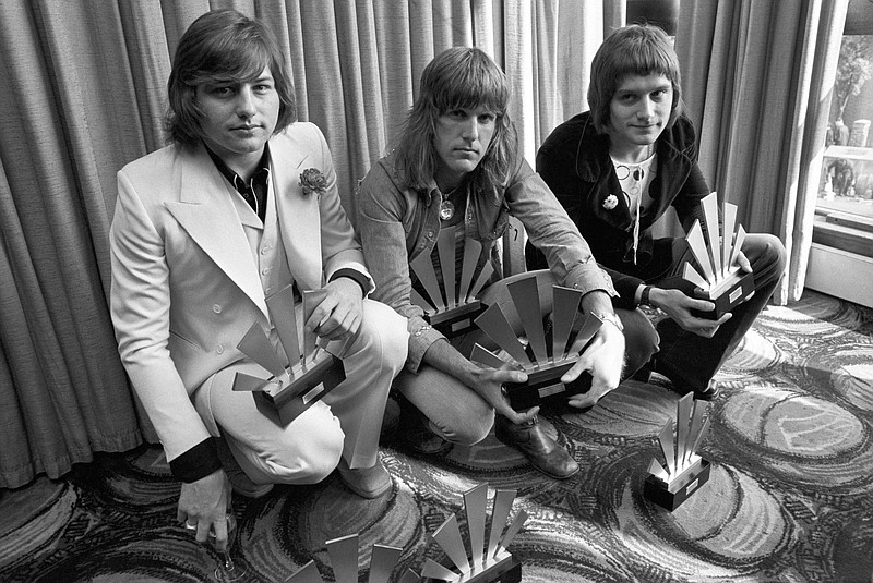 This is a Sept. 30, 1972, file photo of the members of the rock band Emerson, Lake and Palmer, Greg Lake, left Keith Emerson, centre, and Carl Palmer after an award ceremony in London. Greg Lake, the prog-rock pioneer who co-founded King Crimson and Emerson, Lake and Palmer, has died. He was 69. Lake died Wednesday Dec, 7, 2016, after "a long and stubborn battle with cancer," according to his manager. (PA File via AP)