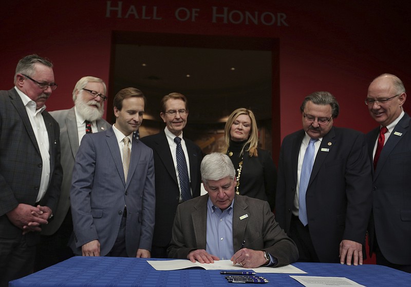 
              Michigan Gov. Rick Snyder signs legislation that establishes comprehensive regulations for the testing, use and eventual sale of autonomous vehicle technology at the Automotive Hall of Fame in Dearborn, Mich., on Friday Dec. 9, 2016.   The package of bills signed into law Friday comes with few specific state regulations and leaves many decisions up to automakers and companies like Google and Uber. It also allows automakers and tech companies to run autonomous taxi services and permits test parades of self-driving tractor-trailers as long as humans are in each truck.  (Romain Blanquart/Detroit Free Press via AP)
            