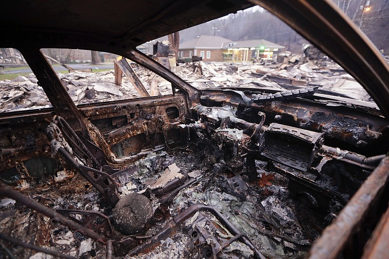 
              FILE- In this Nov. 30, 2016, file photo, a burned car sits in a parking lot in Gatlinburg, Tenn., after a wildfire swept through the area Monday. Authorities on Wednesday, Dec. 7, charged two juveniles in the wildfire that killed over a dozen people and destroyed or damaged more than 1,700 buildings in an iconic tourism spot at the foot of the Great Smoky Mountains. (AP Photo/Mark Humphrey, File)
            