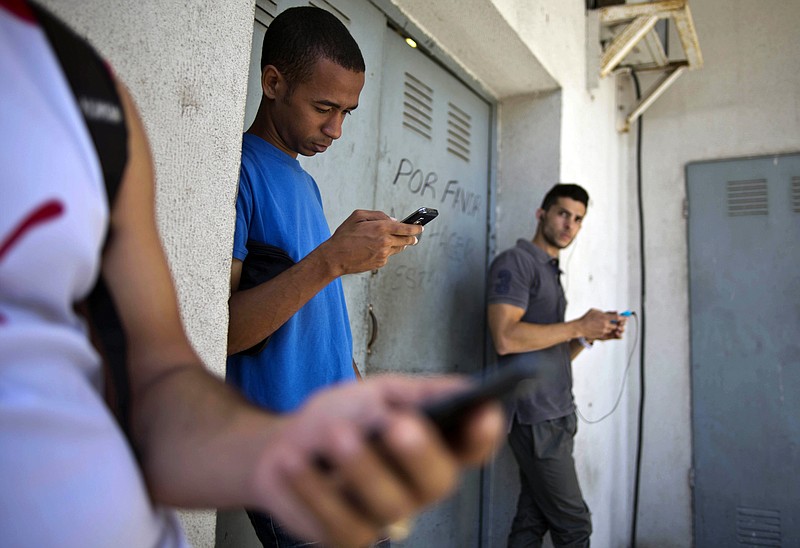 
              FILE - In this April 1, 2014 file photo, students gather behind a business looking for a Internet signal for their smart phones in Havana, Cuba. Google and the Cuban government have struck a deal giving Cubans faster access to the internet giant's content, two people familiar with the deal say. Eric Schmidt, chairman of Google's parent company, will formally sign the deal  in Havana, Monday, Dec. 12, 2016. (AP Photo/Ramon Espinosa, File)
            