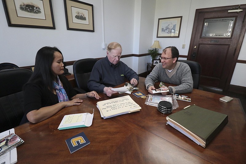 Staff Photo by Dan Henry / The Chattanooga Times Free Press- 12/7/16. Immigration Attorney Terrence L. Olsen, Esq., right, reviews photographs with Glenda and Lewis McCrary as they prepare to apply for a permanent resident card within the next year. 