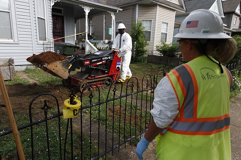 Dena Laborde, right, watches as Cornelius Martin operates a miniature bulldozer to remove soil contaminated with lead from the side yard of a Southside Chattanooga residence off Mitchell Avenue in 2013.