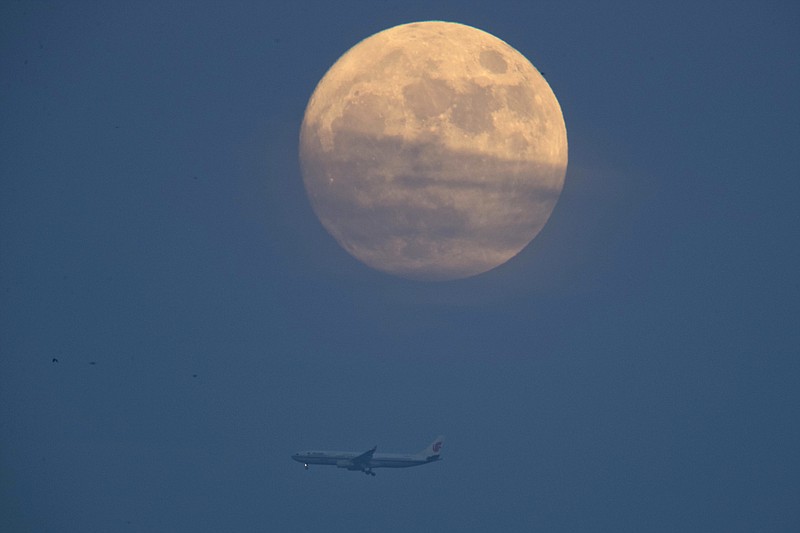 
              A jet liner flies near the supermoon seen from Beijing, China, Tuesday, Dec. 13, 2016. The supermoon phenomenon which occurs when the moon reaches a point closer than usual, shone brightly Tuesday night in Beijing, as the smog that often blankets China's capital city and most of the industrial north in winter subsided for the evening. (AP Photo/Ng Han Guan)
            