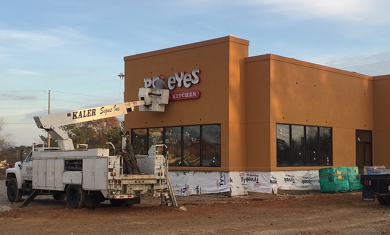 Workers install sign on new Popeyes restaurant, which will open early next year on Highway 58.