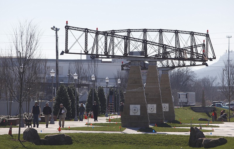 People walk next to the main sculpture work at Main Terrain on Friday afternoon. Work was wrapping up at the new Main Terrain park, located near the Chattanoogan and the Chattanooga Convention Center.