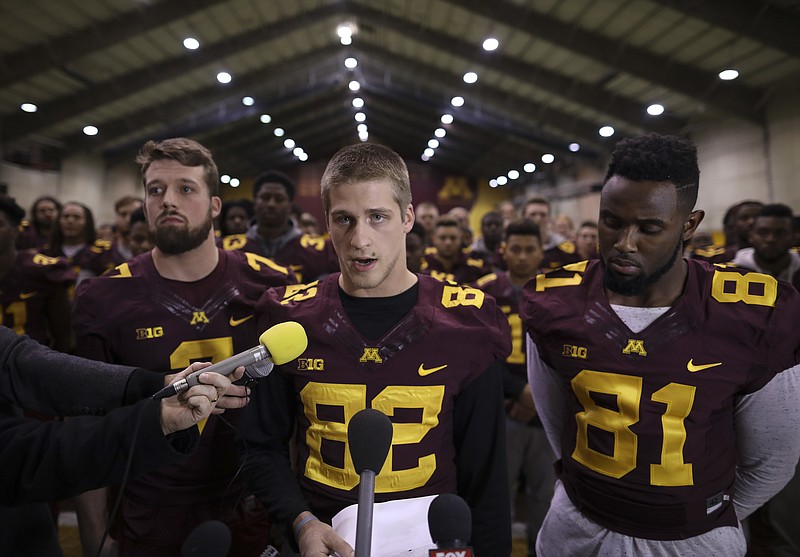 University of Minnesota wide receiver Drew Wolitarsky, flanked by quarterback Mitch Leidner, left, and tight end Duke Anyanwu stands in front of other team members as he reads a statement on behalf of the players in the Nagurski Football Complex in Minneapolis, Minn., Thursday night, Dec. 15, 2016. The players delivered a defiant rebuke of the university's decision to suspend 10 of their teammates, saying they would not participate in any football activities until the school president and athletic director apologized and revoked the suspensions. If that meant they don't play in the upcoming Holiday Bowl against Washington State, they appeared poised to stand firm. (Jeff Wheeler/Star Tribune via AP)

