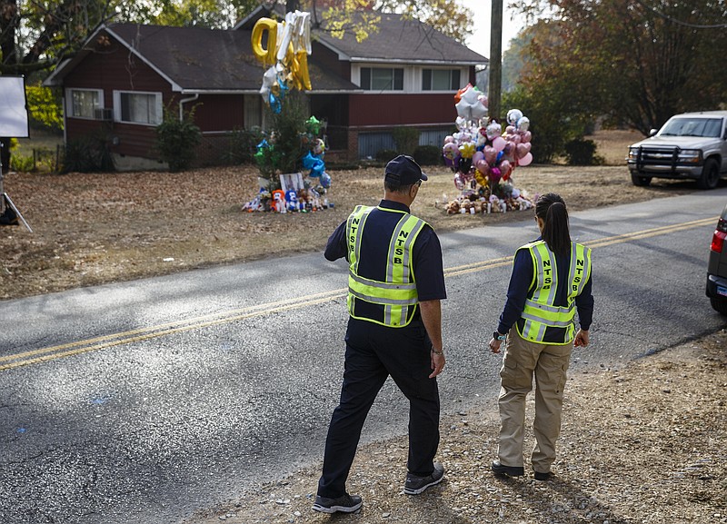 NTSB investigator in charge Robert Accetta, left, and investigator Michele Beckjord examine the road at the site of a fatal school bus crash on Talley Road on Wednesday, Nov. 23, 2016, in Chattanooga, Tenn. A makeshift memorial to victims of the Monday crash, which killed 5 Woodmore Elementary students and injured dozens more, has grown since the road was reopened Tuesday.