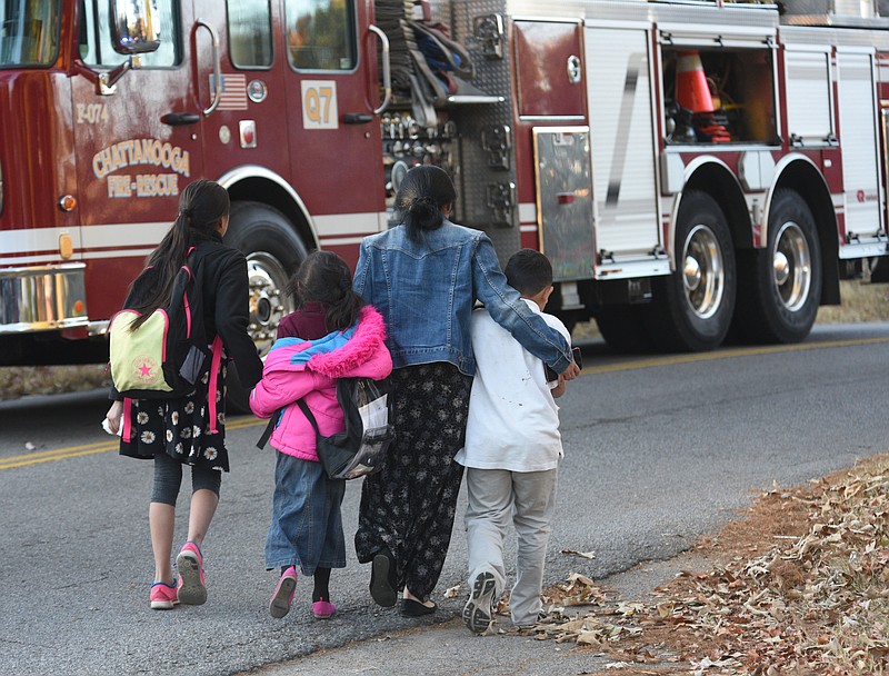 A woman escorts three children away from the scene of a school bus wreck involving multiple fatalities on Talley Road in Chattanooga, Tenn., Monday, Nov. 21, 2016. 