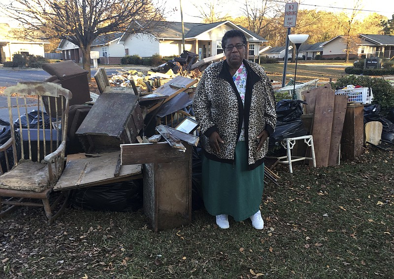 
              In this Dec. 1, 2016 photo, Dianne Hines stands in front of the mound of furniture and other belongings pulled from her home after Hurricane Matthew, in Princeville, N.C. Hines' home was rebuilt after Hurricane Floyd in 1999. This time, she said she's ready to move elsewhere. (AP Photo/Martha Waggoner)
            