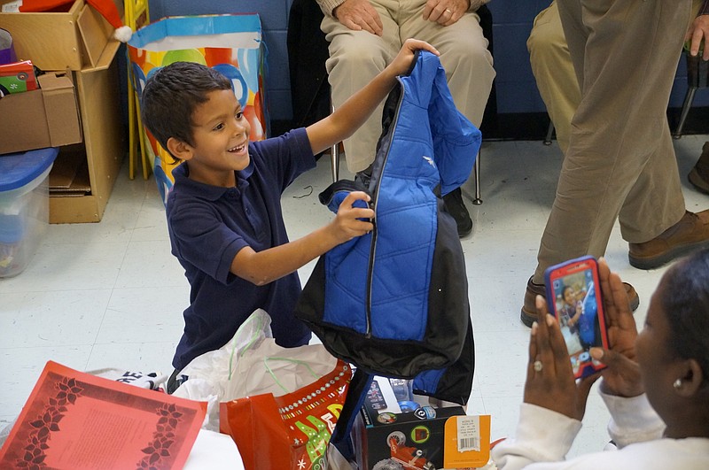 Shakeia, right, takes a picture of her son Ahmad, 6, as he unwraps a brand-new coat. "He's happy," the mother said with a grin. "As long as he's happy."