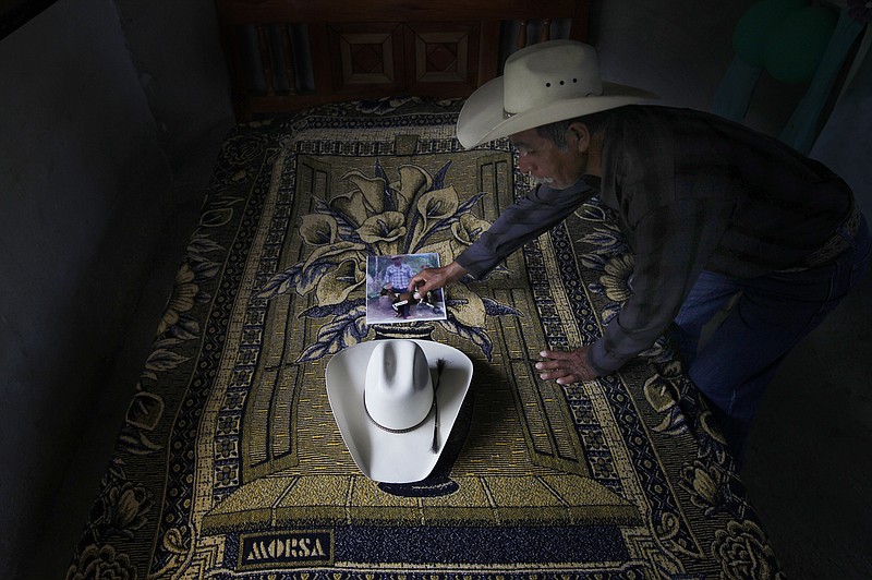 
              ADVANCE FOR USE FRIDAY, DEC. 23, 2016 AND THEREAFTER-In this July 15, 2016 photo, Wenceslao Rangel Gutierrez places a miniature horse statue on a photograph of his late son, Jose, next to his son's hat inside the newly built bedroom at their home in El Sabino, Mexico. The room and bed were paid for using money his son sent home from the U.S. while part of a guest worker program, and was meant as a surprise for him. Jose never got to see his new room, killed in a bus accident when he was on his way back home. (AP Photo/Marco Ugarte)
            