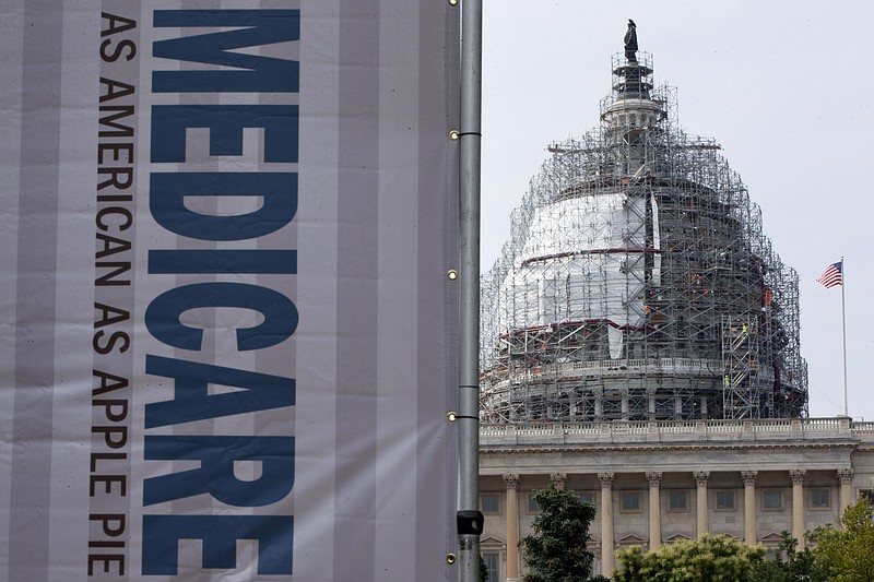 In this July 30, 2015, file photo, a sign supporting Medicare is seen on Capitol Hill in Washington. A government report says Medicare beneficiaries can end up with higher hospital bills for some medical services as outpatients than as inpatients. In the topsy-turvy world of Medicare billing, you may pay more for outpatient care. (AP Photo/Jacquelyn Martin, File)