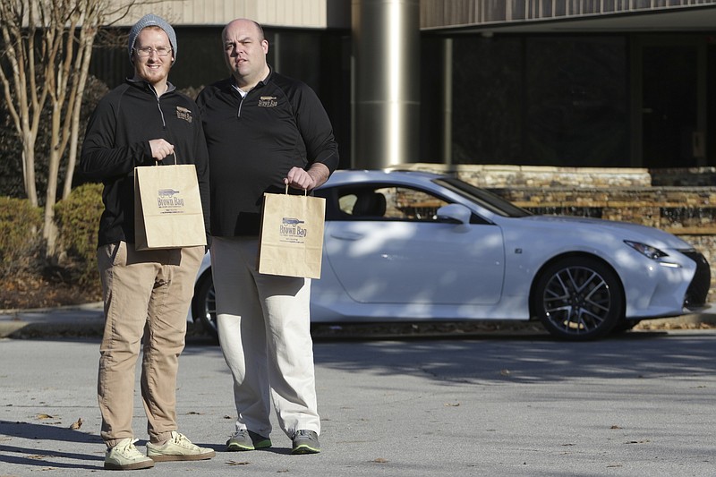 Staff Photo by Dan Henry / The Chattanooga Times Free Press- 12/22/16. Jordan Turner, President of Brown Bag Delivery Chattanooga, left, and Senior Partner DeWayne Williams stand outside of their office on Thursday, December 22, 2016. Brown Bag Delivery Chattanooga is a home alcohol delivery service providing one off bottles to area residents. 