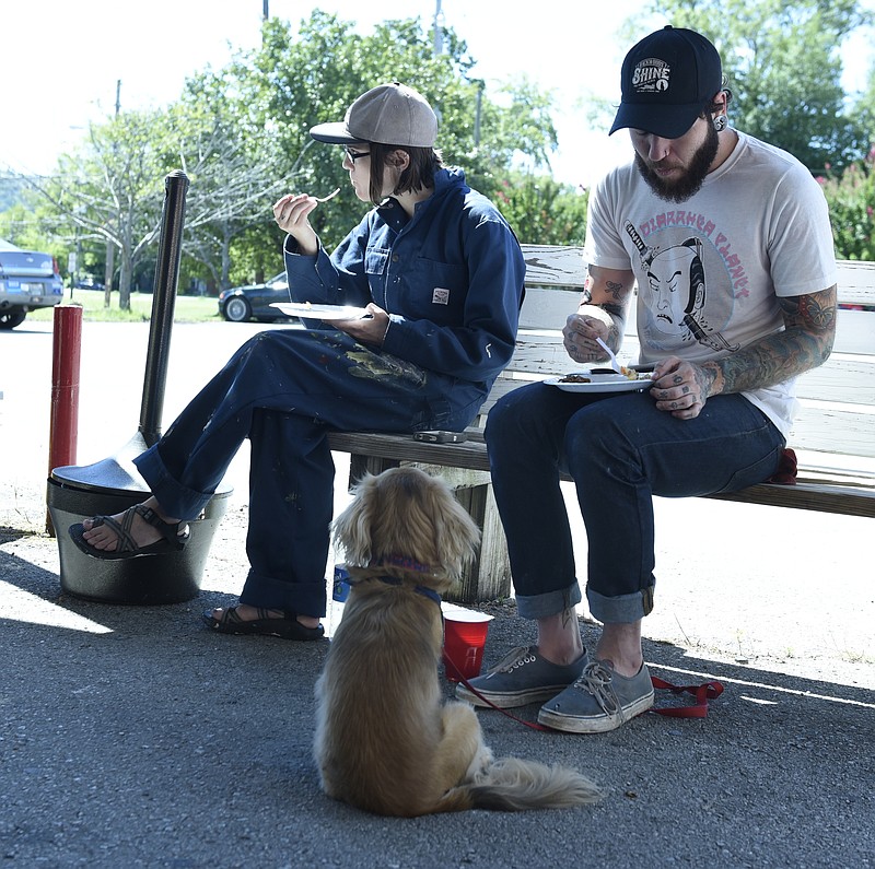 Staff Photo by John Rawlston Ashley Hamilton, left, and Justin Butts eat lunch on a bench while Butts's dog Huey sits and waits after a worship service at the Mercy Junction Justice and Peace Center at St. Andrews in the Highland Park community on Sunday, Sept. 13, 2015, in Chattanooga, Tenn.