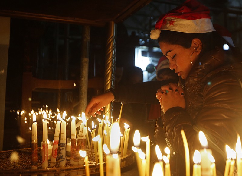 
              A Christian worshipper prays after lighting a candle on Christmas Eve at the Church of the Nativity, built atop the site where Christians believe Jesus Christ was born, in the West Bank City of Bethlehem, Saturday, Dec. 24, 2016. (AP Photo/Majdi Mohammed)
            