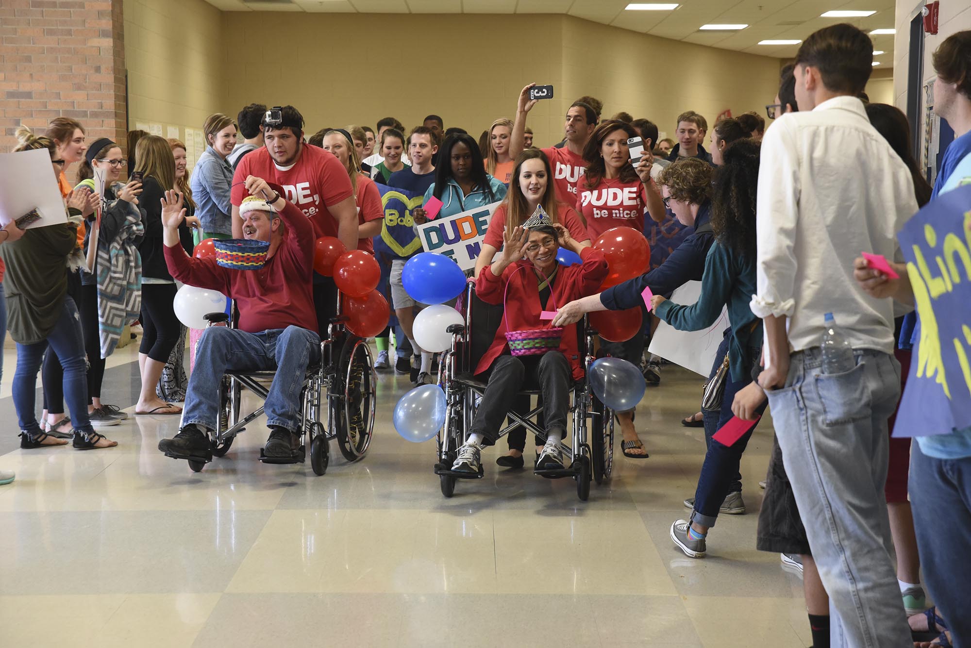 Bobby Hunt, left, custodian, and Adelina "Ling-Ling" Corle, cafeteria worker, are wheeled down the hall Thursday as adoring students honor them at Heritage High School on Thursday.