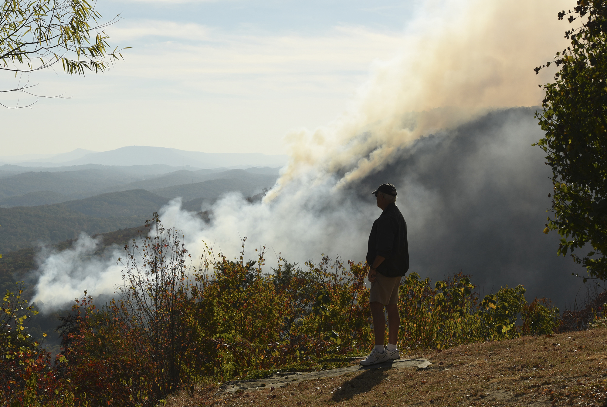 Earl Blanks stands in his Montlake Mountain yard and watches the Flipper Bend fire on the other side of the North Chickamauga Creek late Monday. Crews from Tennessee State Parks, the Tennessee Department of Agriculture Forestry Division and U.S. Forestry Service personnel from the Bureau of Land Management were on scene as two Air National Guard BlackHawk helicopters sporadically dumped water on the expanding blaze.