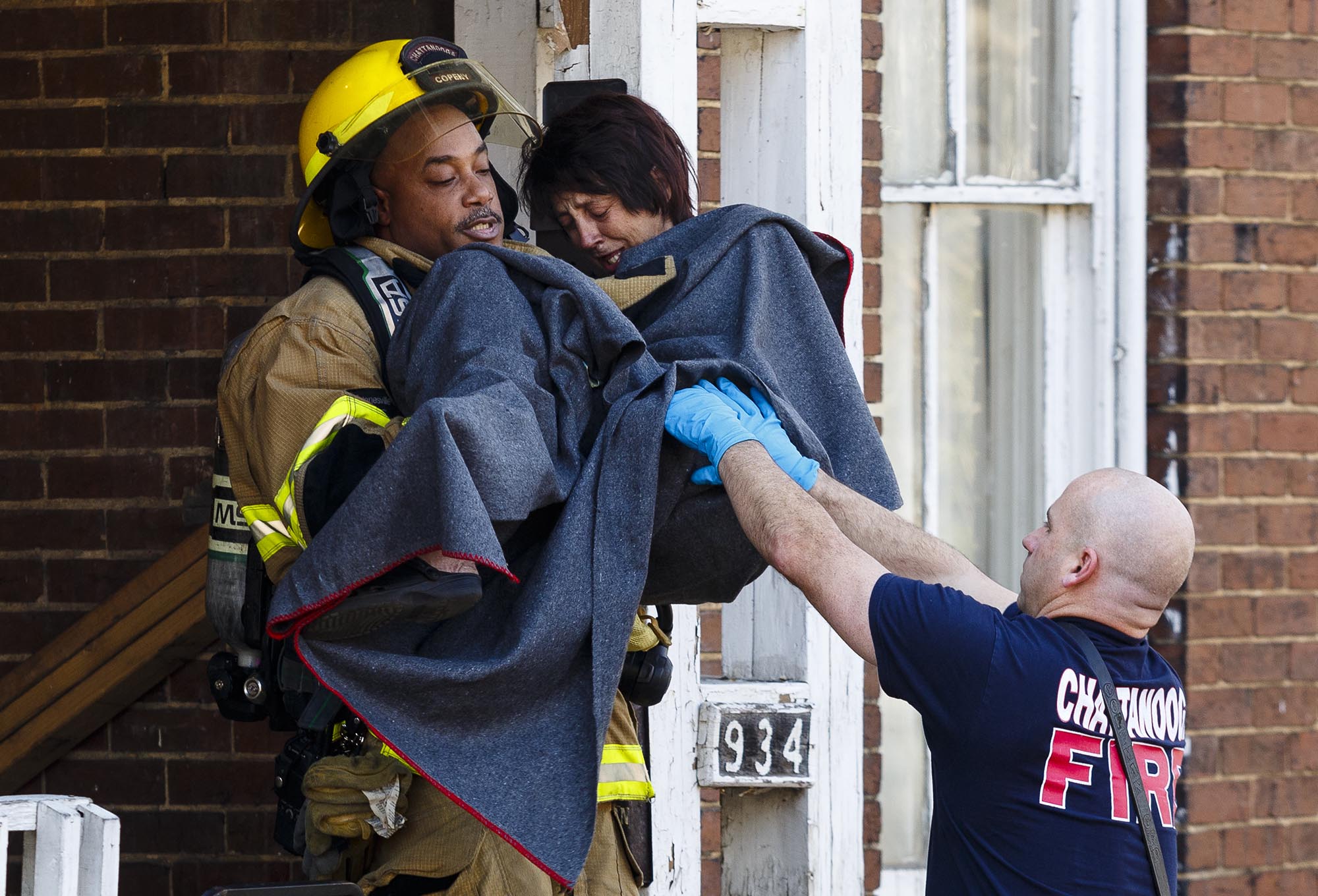 Chattanooga fire Lt. Jerry Copeny carries a woman from the scene of a residential fire at 934 East 10th Street on Sunday, Dec. 25, 2016, in Chattanooga, Tenn. According to the Chattanooga Fire Department, the victim was treated for first degree burns to both hands and smoke inhalation on the scene before being transported to Erlanger Hospital.