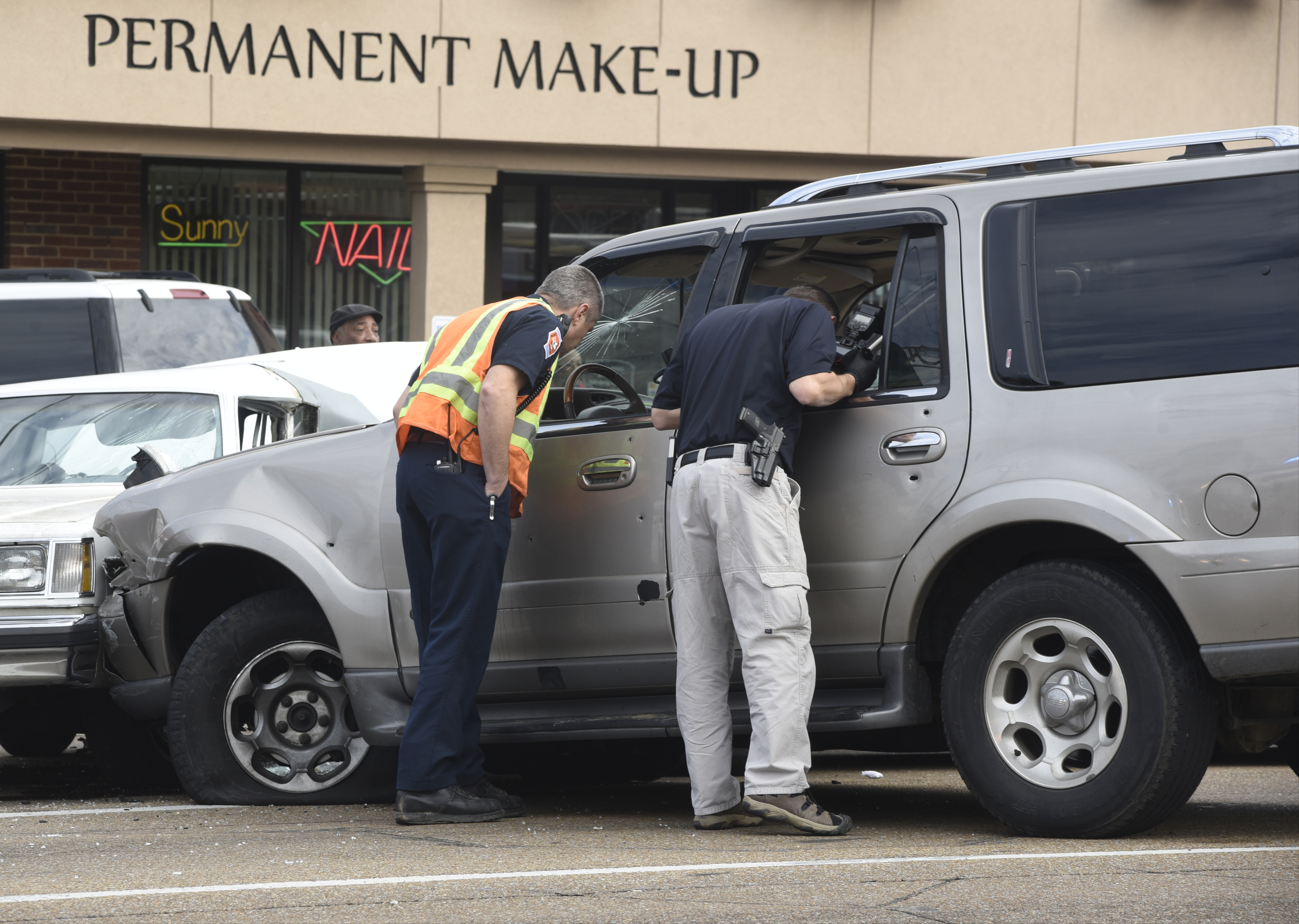 Chattanooga police look at a gold Lincoln Navigator that was struck by at least nine bullets before swerving into oncoming traffic causing a multi-vehicle accident in the 5300 block of Brainerd Road on Wednesday, Feb. 3, 2016, in Chattanooga, Tenn.