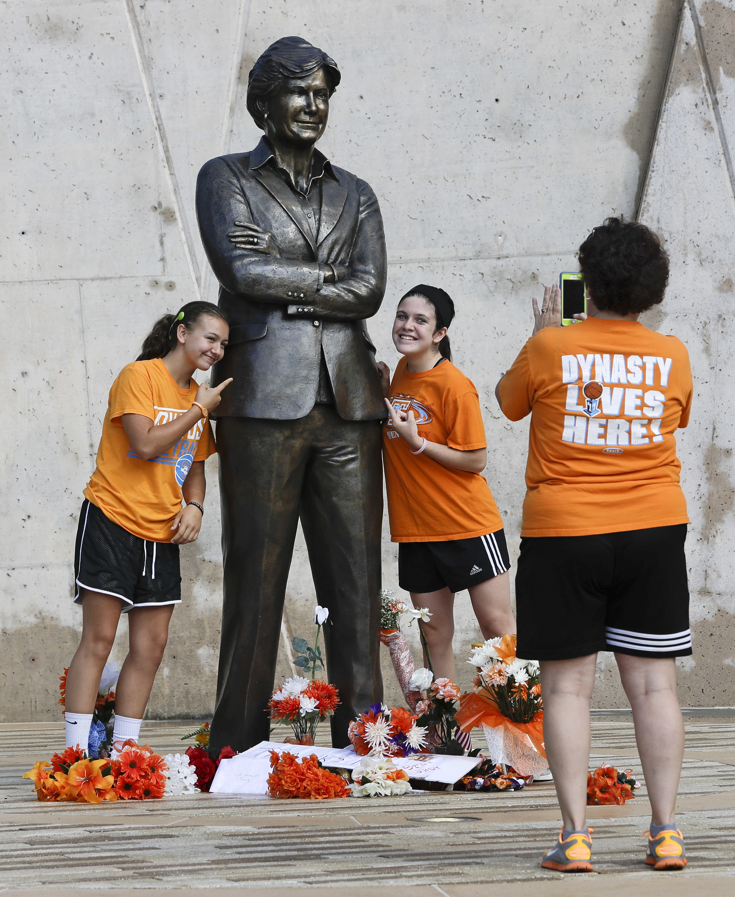 Katrina Nix, right, takes a photo of Mykenzie Weaber, 15, left, and Emma Nix, 15, all of Jasper, Ga., at the statue of former Tennessee women's basketball coach Pat Summitt on the Tennessee campus Thursday, July 14, 2016, in Knoxville, Tenn. A a ceremony to celebrate the life of Summitt is scheduled for Thursday evening in the university's basketball arena. Summitt died June 28 at the age of 64. (AP Photo/Mark Humphrey)