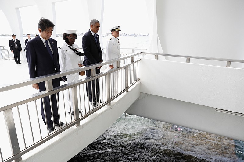 U.S. President Barack Obama and Japanese Prime Minister Shinzo Abe pause after tossing flower petals into the Wishing Well at the USS Arizona Memorial, part of the World War II Valor in the Pacific National Monument, in Joint Base Pearl Harbor-Hickam, Hawaii, adjacent to Honolulu, Hawaii, Tuesday, Dec. 27, 2016, as part of a ceremony to honor those killed in the Japanese attack on the naval harbor. (AP Photo/Carolyn Kaster)